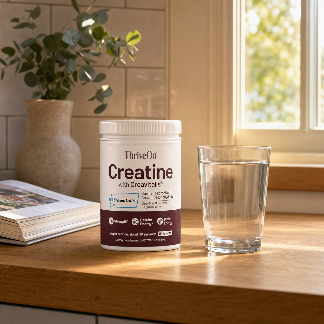ThriveOn Creatine tub on a kitchen counter beside a glass of water in morning light