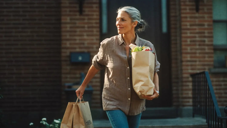 Woman in her fifties carrying two grocery bags up her front steps, the everyday strength creatine for sarcopenia protects