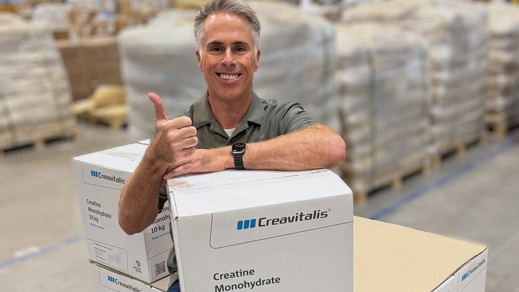 ThriveOn co-founder Andrew O'Hare gives a thumbs up beside 10 kg cartons of Creavitalis® creatine monohydrate