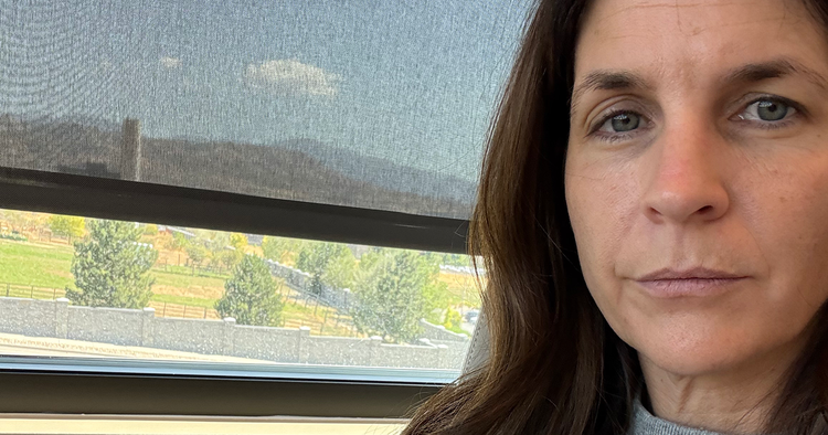 Victoria O'Hare, ThriveOn co-founder, looking directly at the camera with a flat, tired expression beside a window.